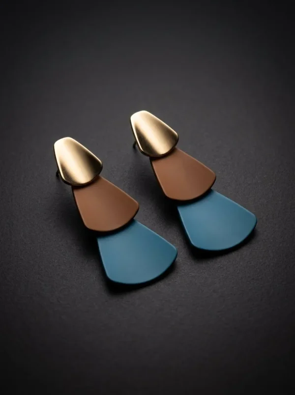 Aretes Monolito Azul de Arcano: tres piezas geométricas en cascada en dorado, terracota y azul petróleo
