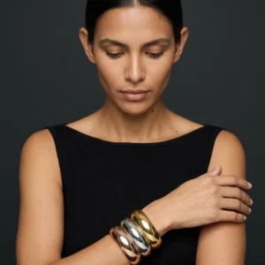 Trío Eclipse de Arcano: retrato editorial con los tres brazaletes de domo en oro rosa, plata y oro