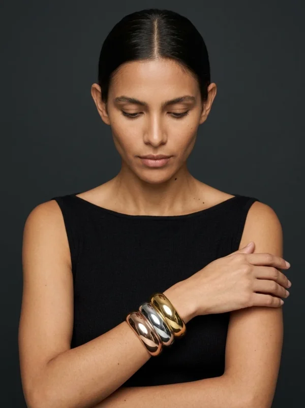 Trío Eclipse de Arcano: retrato editorial con los tres brazaletes de domo en oro rosa, plata y oro